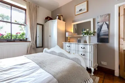 a bedroom with a white bed and a dresser at The Old Coastguard Station in Falmouth