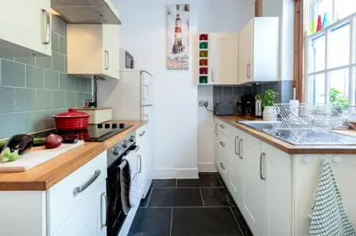 a kitchen with white cabinets and black tile floors at The Old Coastguard Station in Falmouth