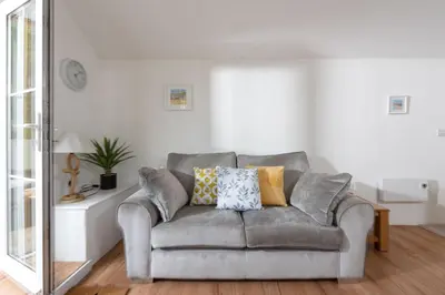 a living room with a gray couch and a mirror at Kerensa in Portreath