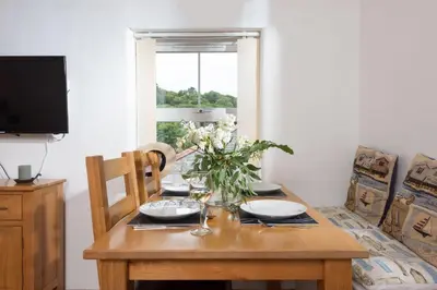 a dining room table with a vase of flowers on it at Kerensa in Portreath