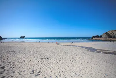 a beach with people walking on the sand and the ocean at Kerensa in Portreath