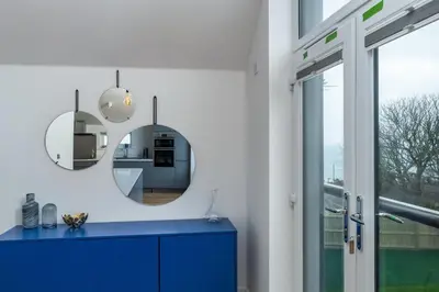 a bathroom with a blue cabinet and two mirrors at Waves Falmouth-hot tub games room very close to Swanpool beach and Falmouth GC in Falmouth