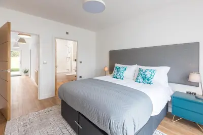 a bedroom with a large bed with blue pillows at Waves Falmouth-hot tub games room very close to Swanpool beach and Falmouth GC in Falmouth