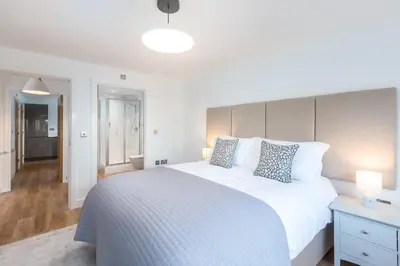 a bedroom with a large white bed and a hallway at Waves Falmouth-hot tub games room very close to Swanpool beach and Falmouth GC in Falmouth