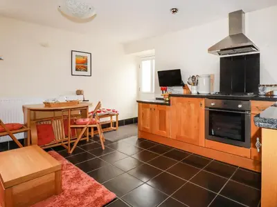 a kitchen with a stove and a dining room at Grainstore in Tintagel