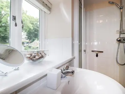 a bathroom with a sink and a mirror and a window at Grainstore in Tintagel