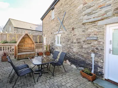 a patio with a table and chairs next to a brick building at Grainstore in Tintagel