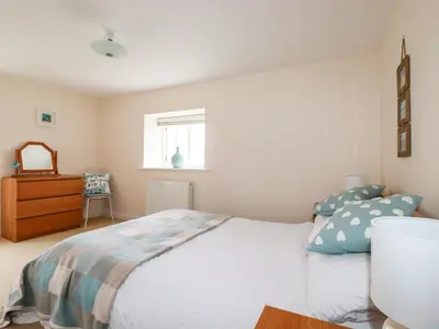 a bedroom with a bed and a dresser and a window at Grainstore in Tintagel