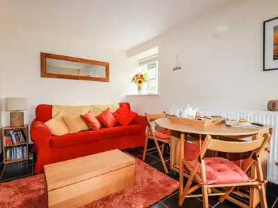 a living room with a red couch and a table at Grainstore in Tintagel