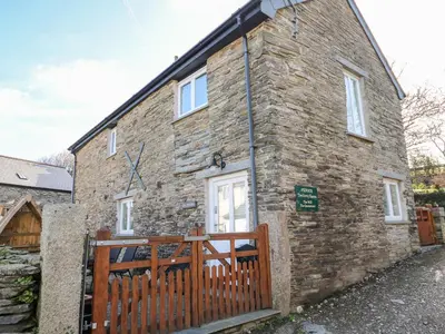 a brick house with a wooden fence in front of it at Grainstore in Tintagel