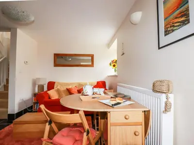 a living room with a table and a red couch at Grainstore in Tintagel