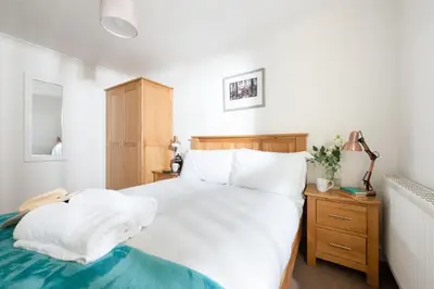 a bedroom with a white bed and a wooden cabinet at Rosebud in Portreath