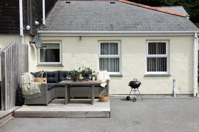 a patio with a sofa and a table in front of a house at Rosebud in Portreath