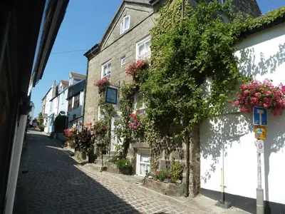 a cobblestone street with flowers on buildings at The Grey Mullet Guest House in St Ives