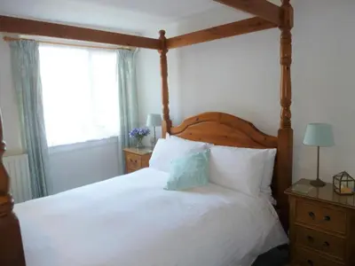 a bedroom with a large bed with a wooden canopy at The Grey Mullet Guest House in St Ives