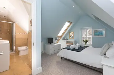a bedroom with a bed and a bathroom with a toilet at Happy Days in St Ives