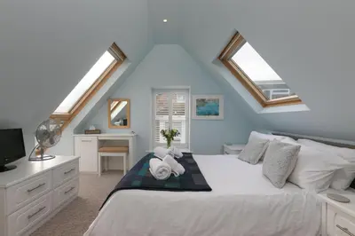a bedroom with a large white bed with a window at Happy Days in St Ives