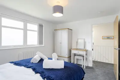 a bedroom with a bed and a desk and window at The Cube in Portreath