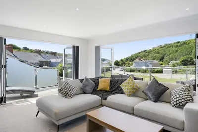 a living room with a white couch and large windows at The Cube in Portreath
