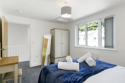 a bedroom with a bed and a desk and windows at The Cube in Portreath