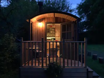 a wooden gazebo with a table on a porch at Brook the Shepherd Hut in Saltash