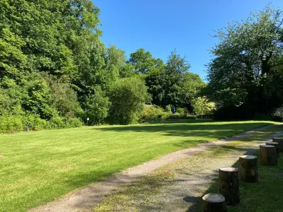 a dirt road in a grass field with trees at Brook the Shepherd Hut in Saltash