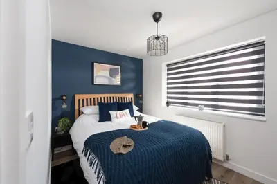 a bedroom with a bed with a blue accent wall at Bay Dream - Free parking, close to beach, pet friendly in Carbis Bay