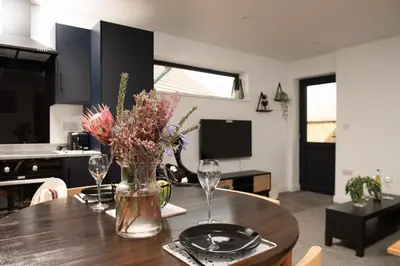 a dining room table with a vase of flowers on it at Bay Dream - Free parking, close to beach, pet friendly in Carbis Bay