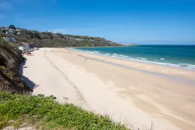 a beach with people walking on the sand and the ocean at Bay Dream - Free parking, close to beach, pet friendly in Carbis Bay