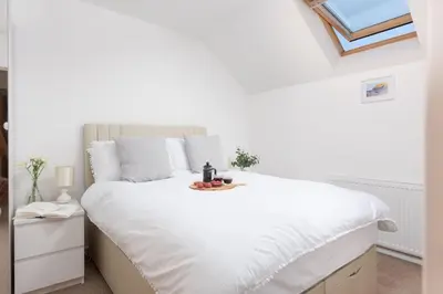 a white bedroom with a large bed with white sheets at 7 Trevose House, St Ives in Carbis Bay