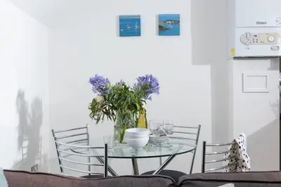 a glass table with chairs and a vase of flowers at 7 Trevose House, St Ives in Carbis Bay