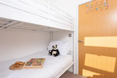 a teddy bear sitting on a bed with a book at 7 Trevose House, St Ives in Carbis Bay