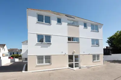 a white building with windows on a street at 7 Trevose House, St Ives in Carbis Bay