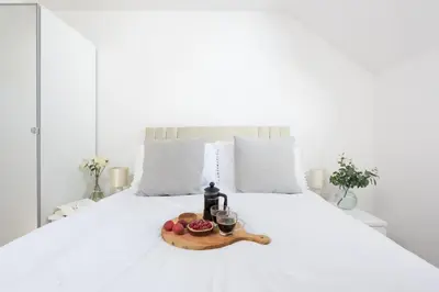 a tray with a bottle of wine and fruit on a bed at 7 Trevose House, St Ives in Carbis Bay