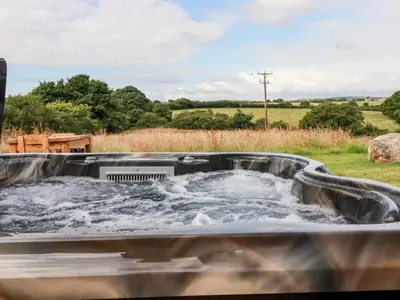 a hot tub with water in a field at The Olju in Truro
