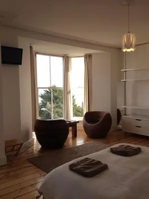 a bedroom with two chairs and a bed and a window at organic panda in St Ives