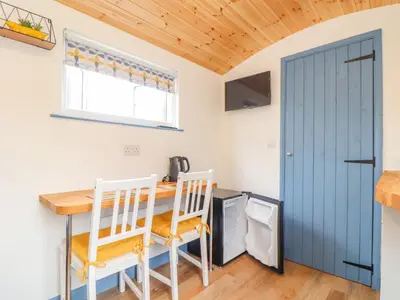 a kitchen with a table and chairs and a blue door at Sunflower in Redruth