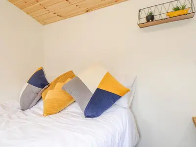 a bed with four pillows on it with a white bed at Sunflower in Redruth