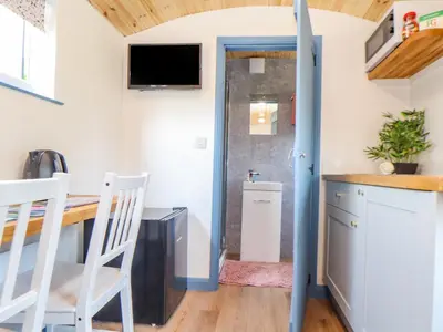 a kitchen with a table and chairs in a tiny house at Rose in Redruth