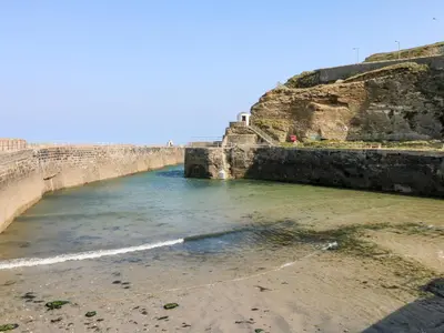 a body of water next to a stone wall at Rose in Redruth