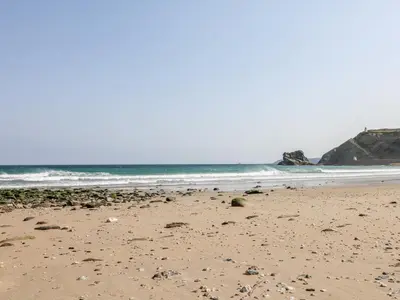 a sandy beach with rocks in the ocean at Rose in Redruth