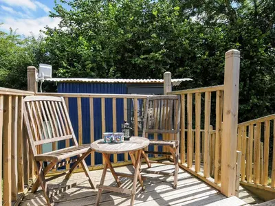 a table and two chairs on a wooden deck at Shepherds Hut in Lostwithiel