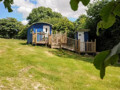two portable toilets in a grassy field with trees at Shepherds Hut in Lostwithiel