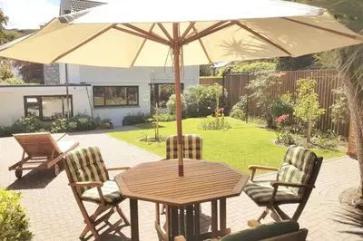 a wooden table with two chairs and an umbrella at High quality detached house with parking St. Ives in St Ives