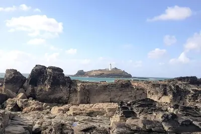 a lighthouse on a rocky island in the ocean at High quality detached house with parking St. Ives in St Ives