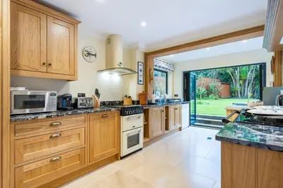 a large kitchen with wooden cabinets and a large window at High quality detached house with parking St. Ives in St Ives