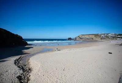a beach with a person standing on the sand at Rosevilla Farmhouse in Portreath