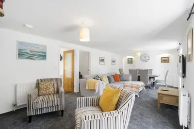 a living room with couches and chairs and a table at Rosevilla Farmhouse in Portreath