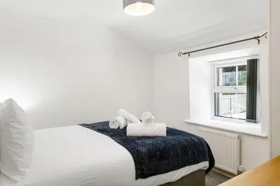 a white bedroom with a bed with towels on it at Rosevilla Farmhouse in Portreath
