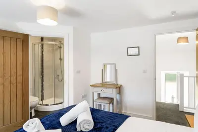 a bedroom with a bed and a bathroom with a shower at Rosevilla Farmhouse in Portreath